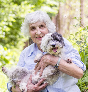 Senior smiling woman hugging her dog in the mountain